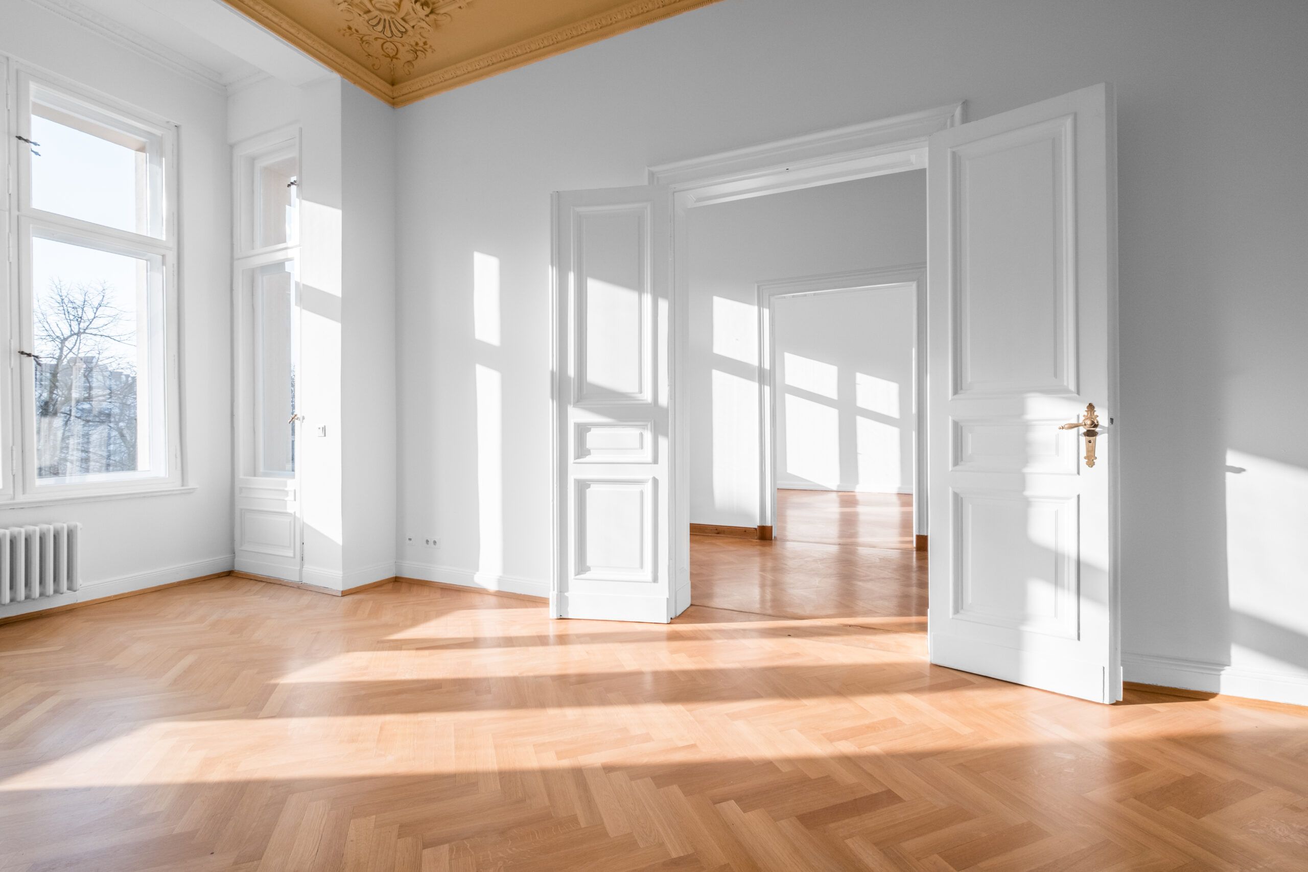 Stanza vuota, appartamento con soffitto a stucco e pavimento in parquet, infissi e porta bianchi