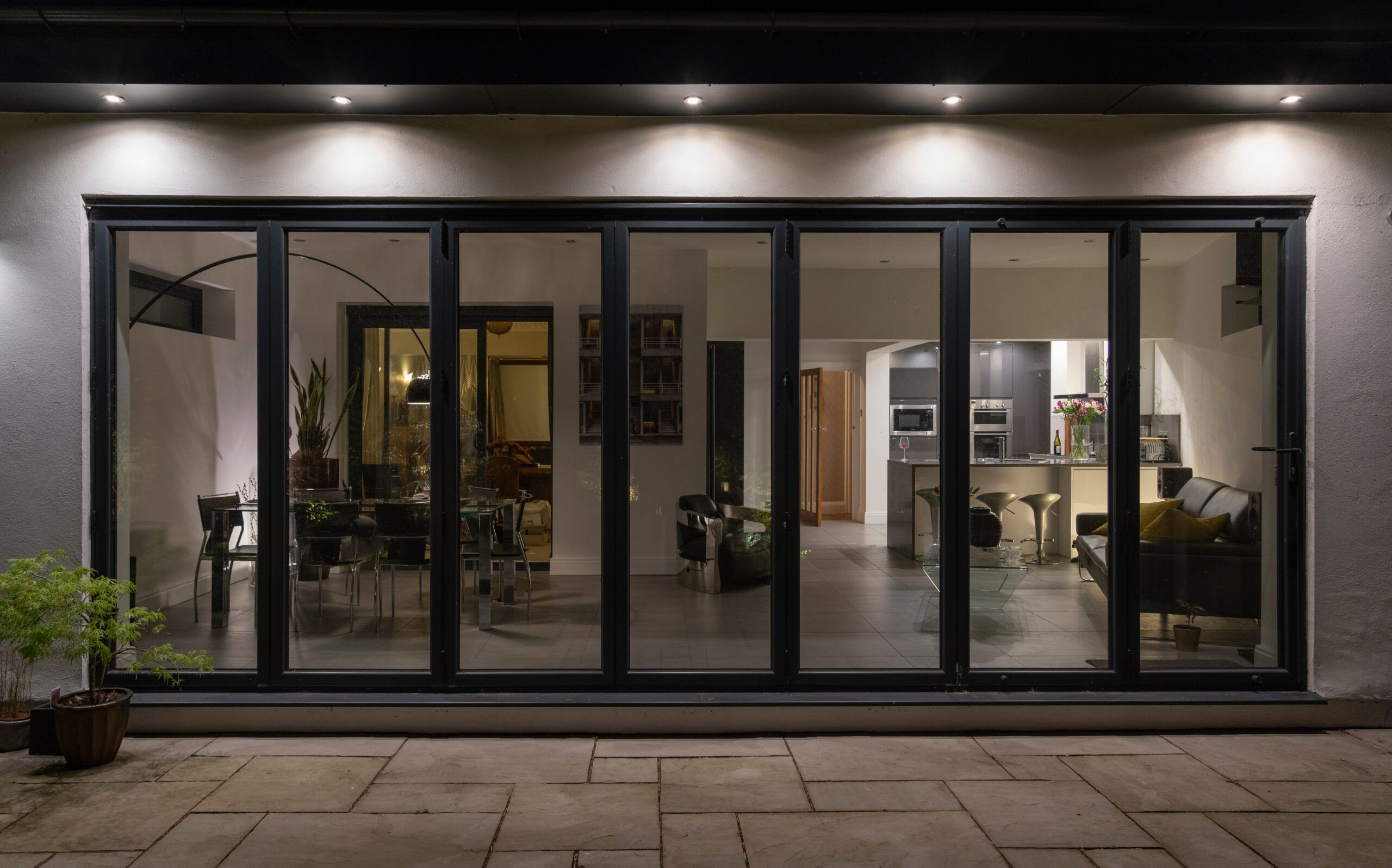 Eleganti porte vetrate a soffietto di notte, con gli illuminatori che svelano gli interni